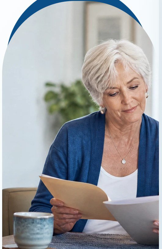 Older woman reviewing paperwork at her kitchen table